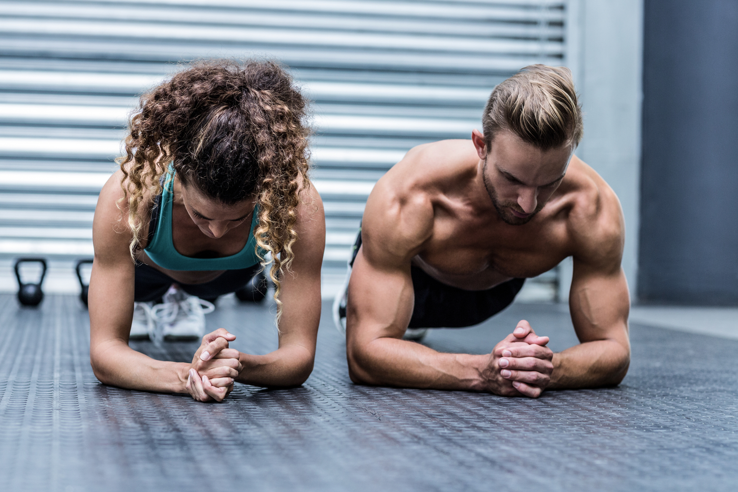 Front view of a muscular couple doing planking exercises