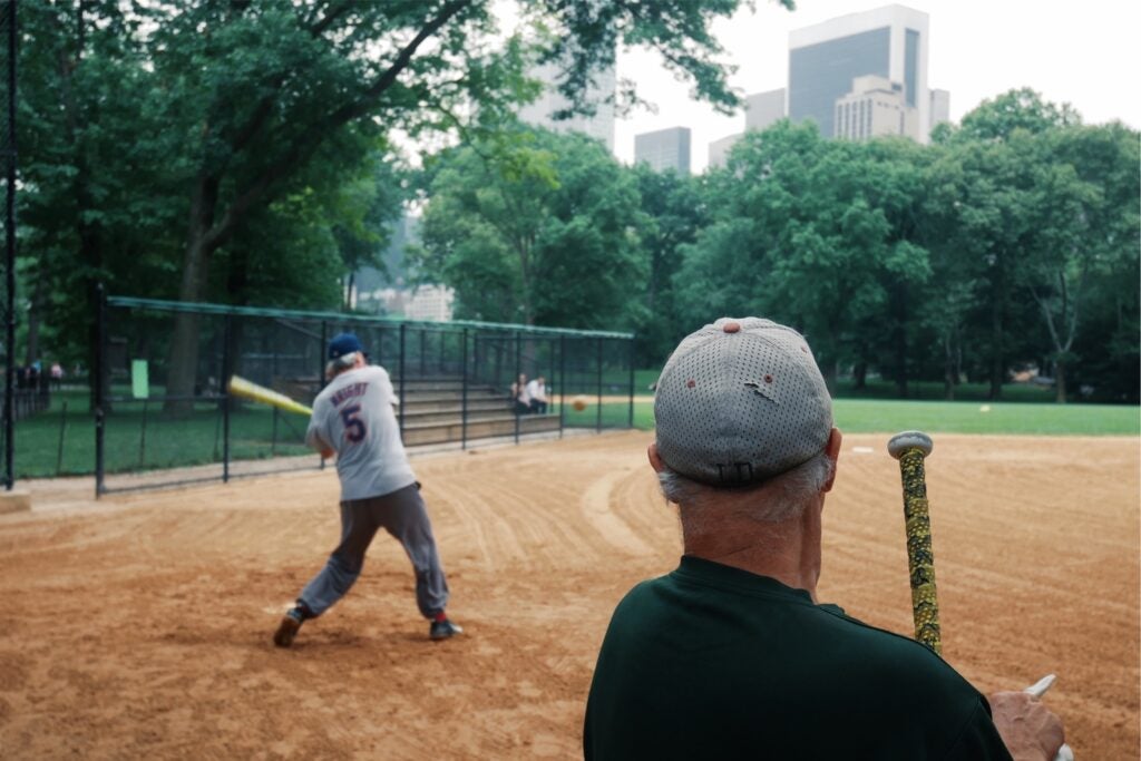 a man swinging a softball bat in Central Park