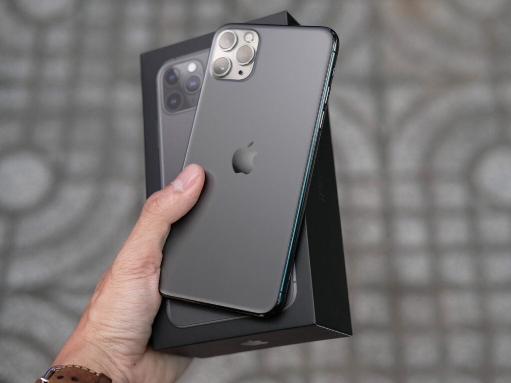 Hand holding an iPhone 11 and its box