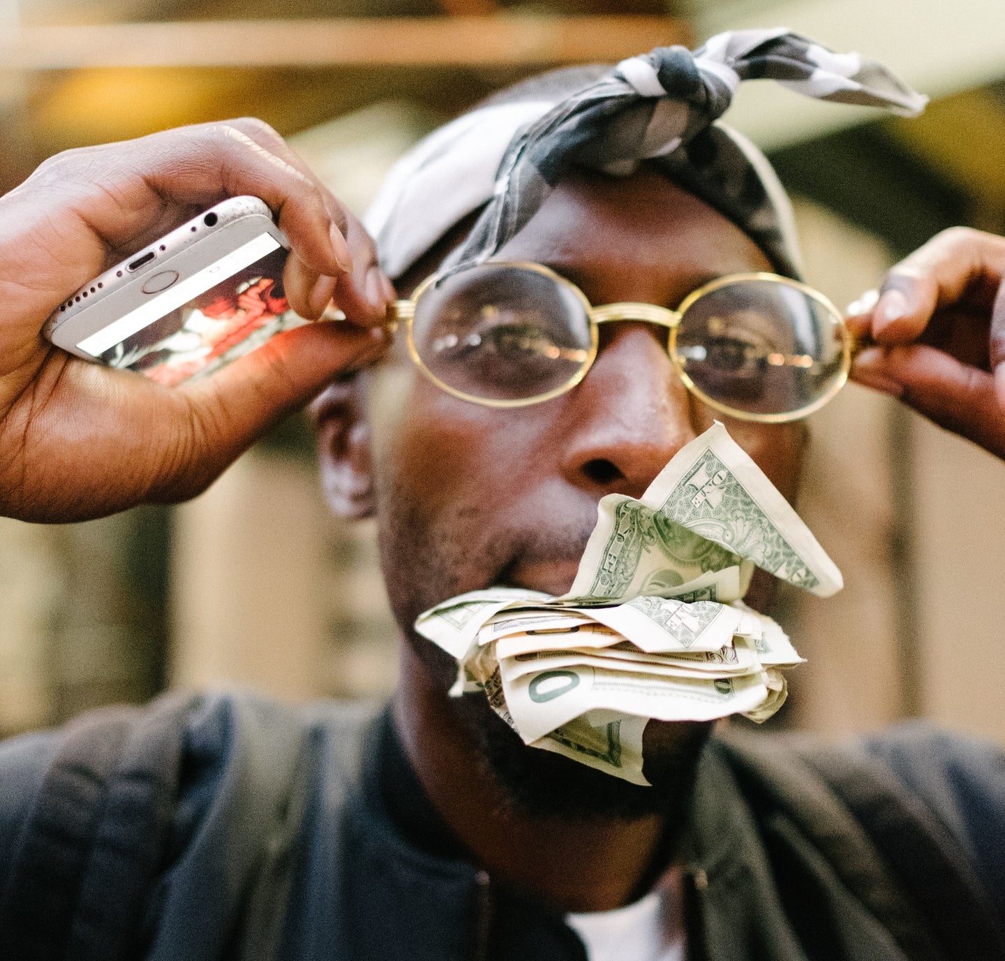 a man wearing sunglasses while holding cash money in his mouth