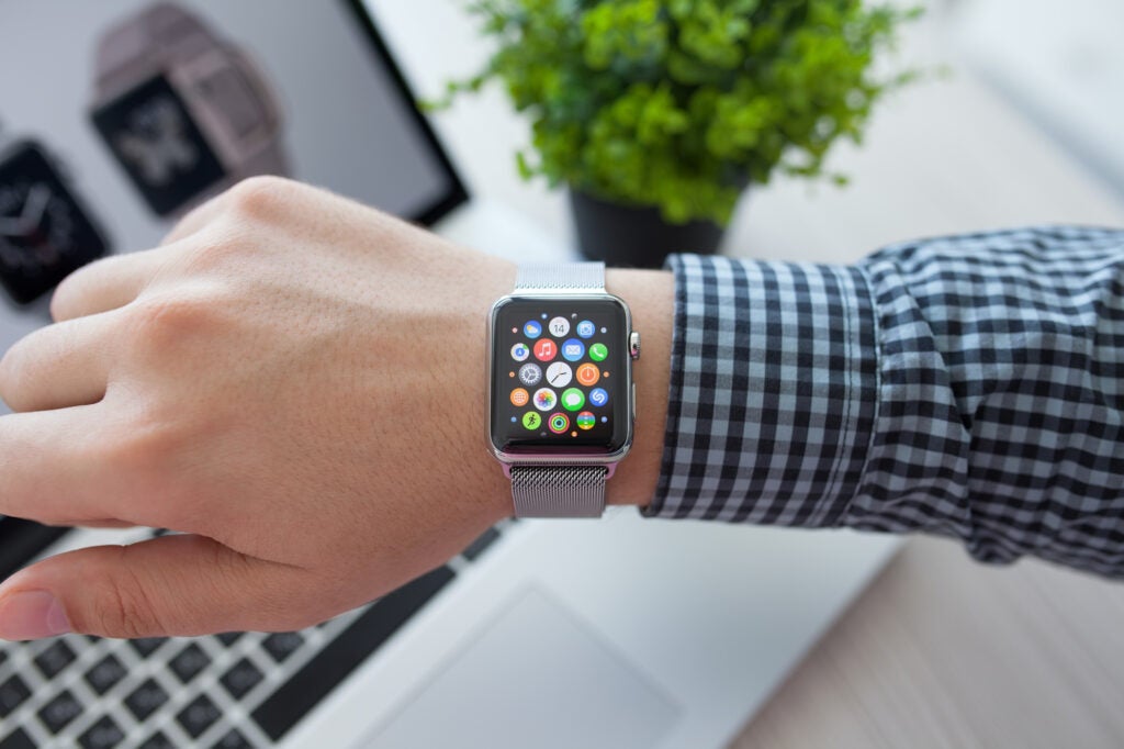 Hand with an apple watch in front of a macbook