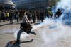 Person kicking teargas canister in Paris protests