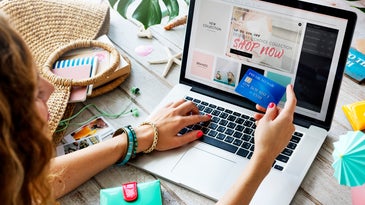 Person online shopping and holding credit card in front of computer on