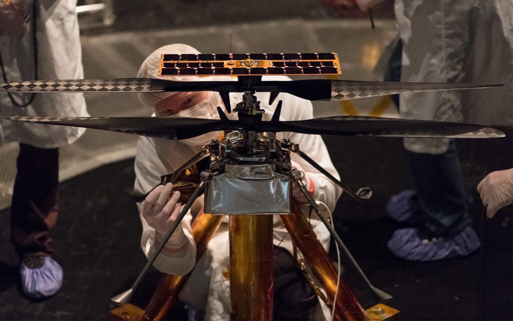 a man touching the NASA's Ingenuity Mars Helicopter