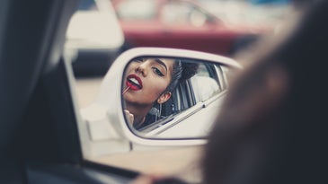 woman putting lipstick on in a car