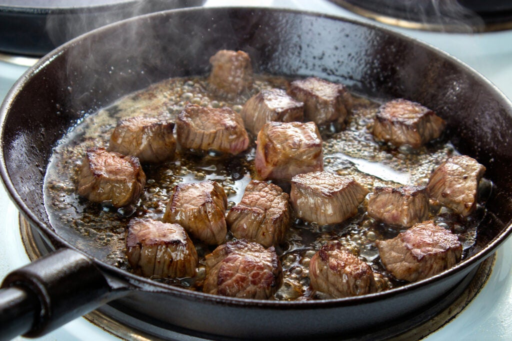 Frying beef bottom round roast cubes in cast iron skillet