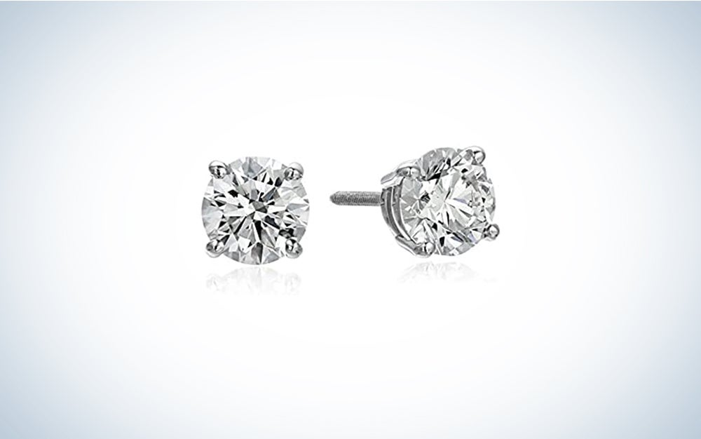 A pair of Amazon Collection IGI Platinum Round Cut Diamond Stud Earrings on a blue and white background