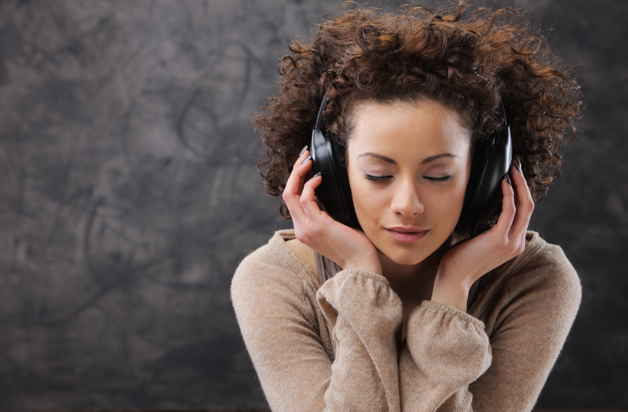 a woman with her eyes closed listening to something with headphones