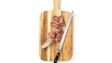 Salami cut on cutting board with knife.