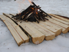A fire built on planks of wood to keep dry from the snow.