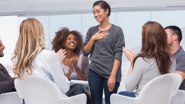 a woman standing up and smiling in group therapy
