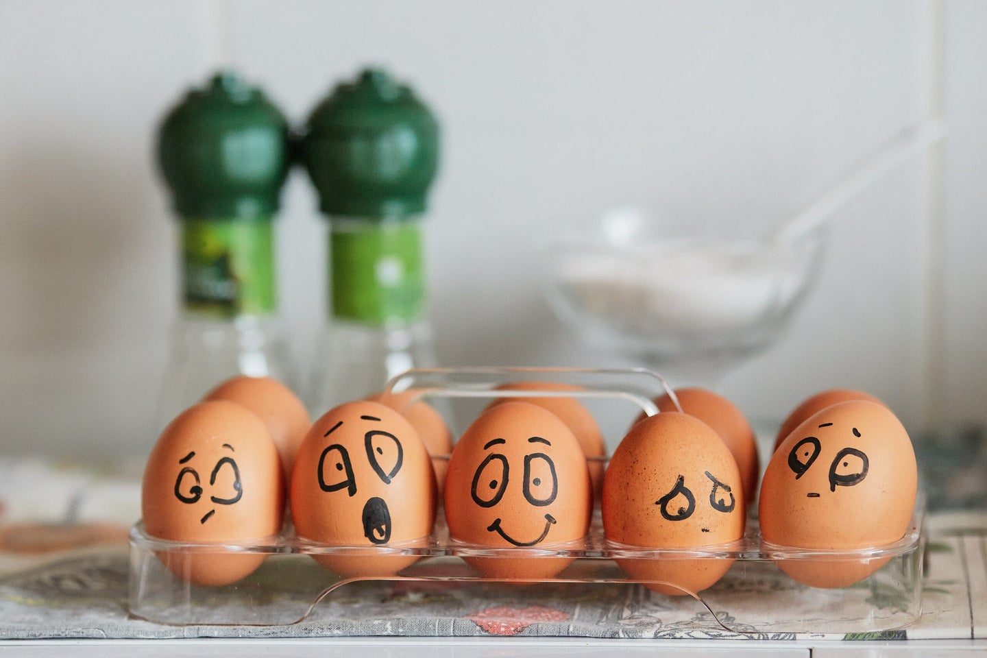 A carton of brown eggs with faces drawn on