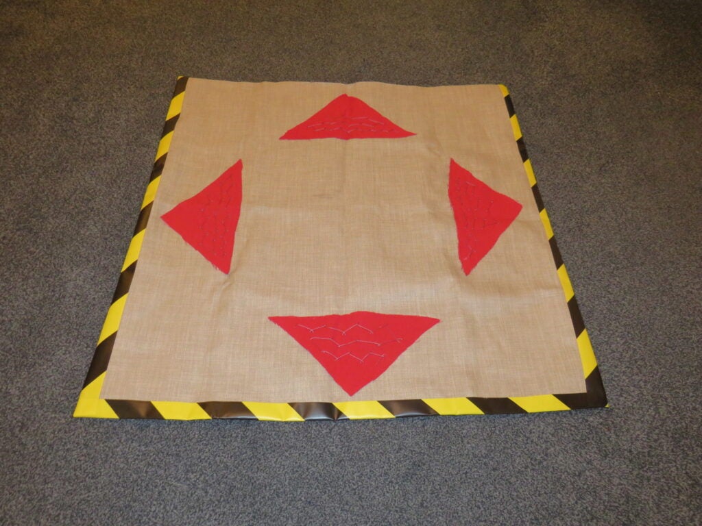 a DIY homemade dance mat for a dance arcade game, made of fabric and tape, with conductive thread