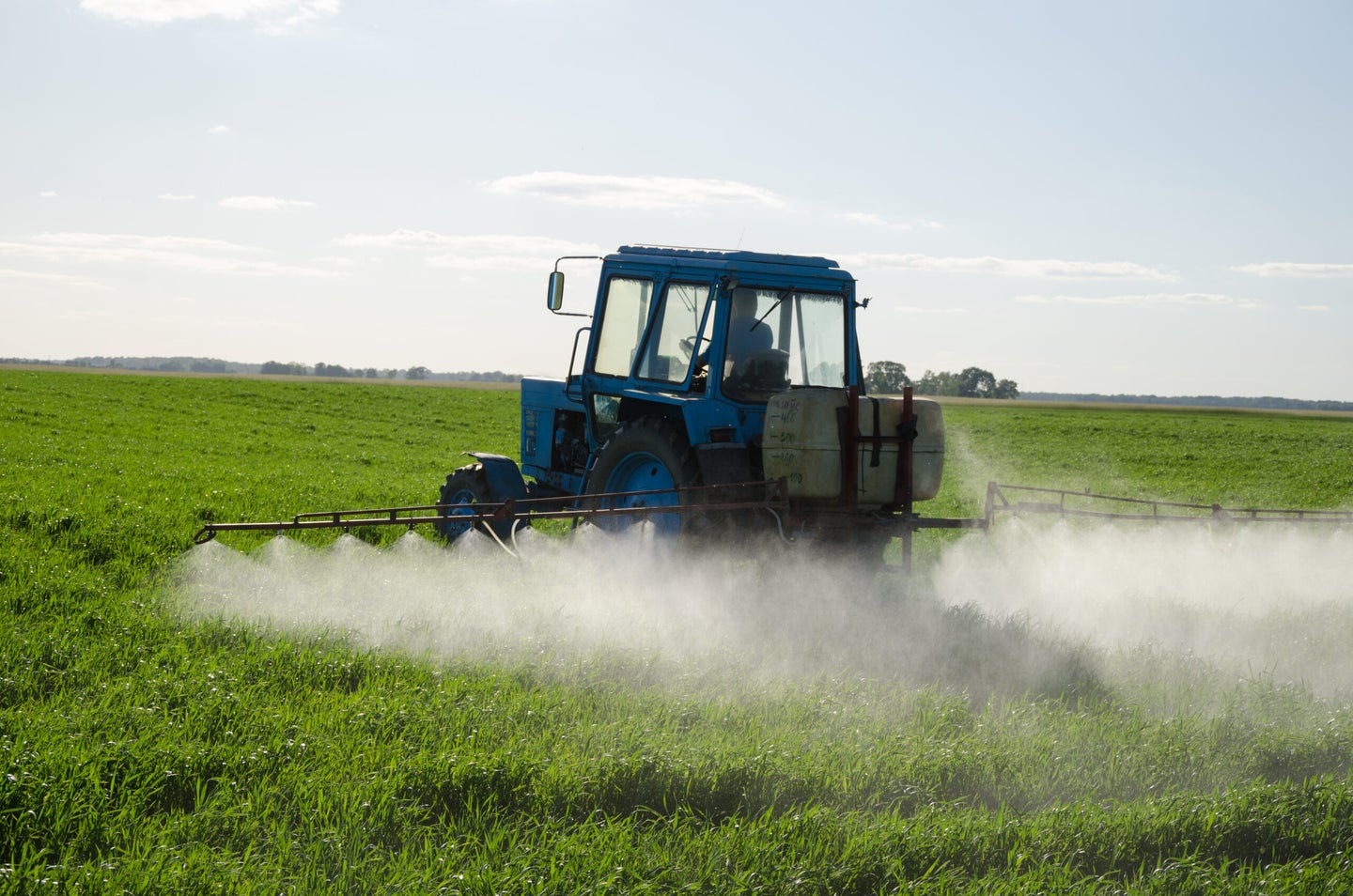 tractor spraying insecticide over field