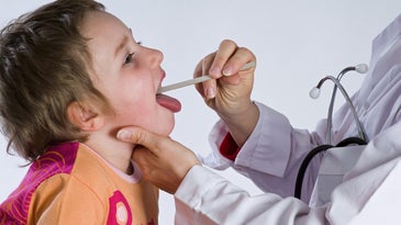 a doctor uses a tongue depressor to look down a child's throat