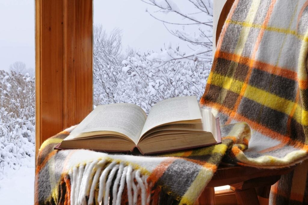 Book on chair with a blanket and snow in the background