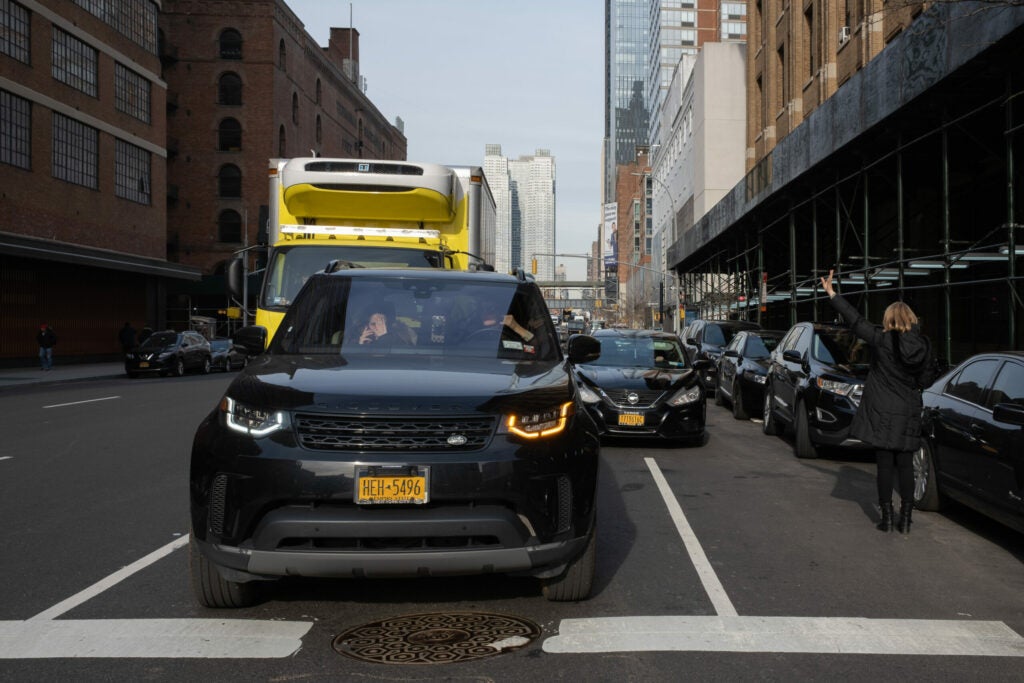 Pedestrian hailing a cab in New York traffic