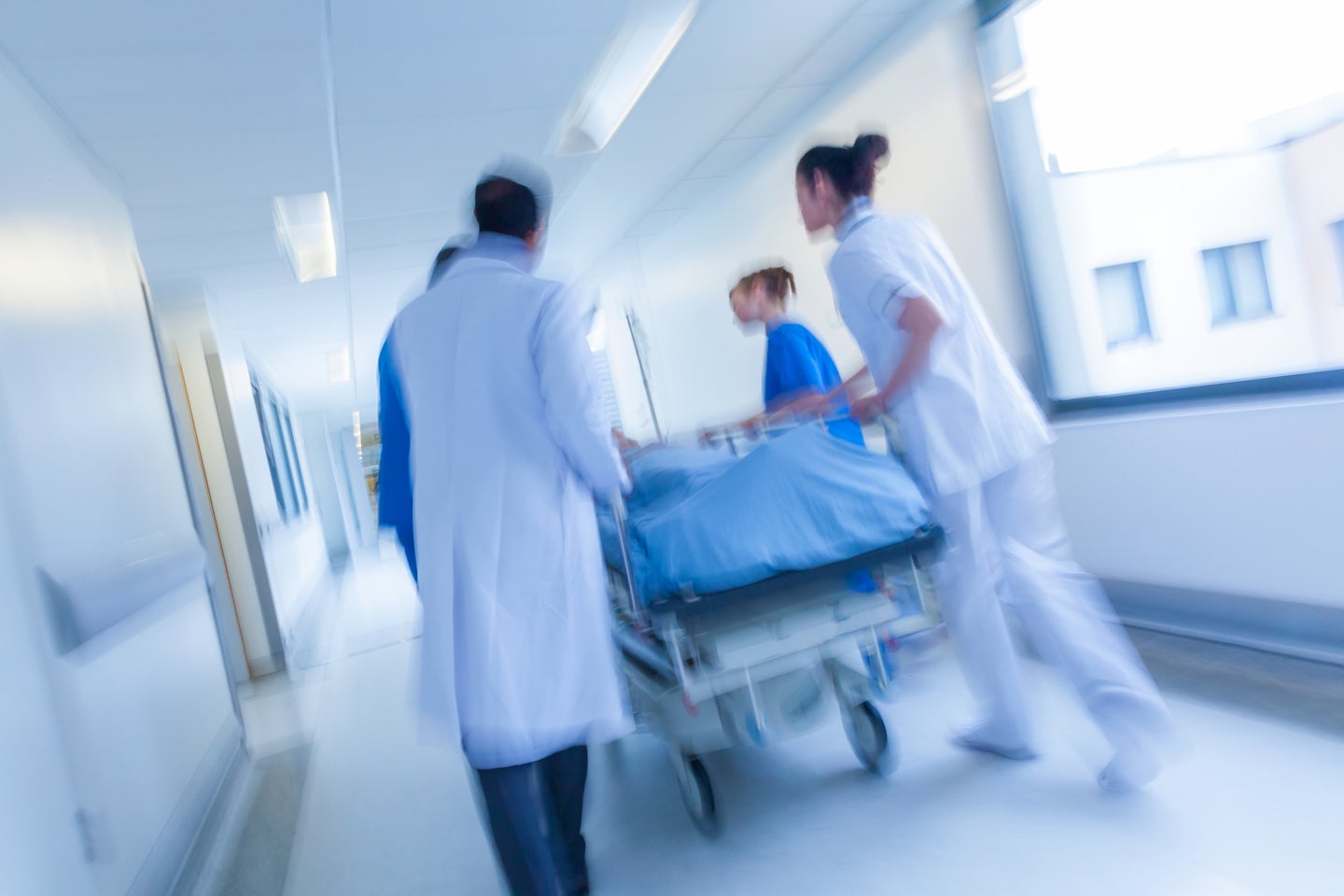 a blurred shot of hospital workers wheeling a gurney