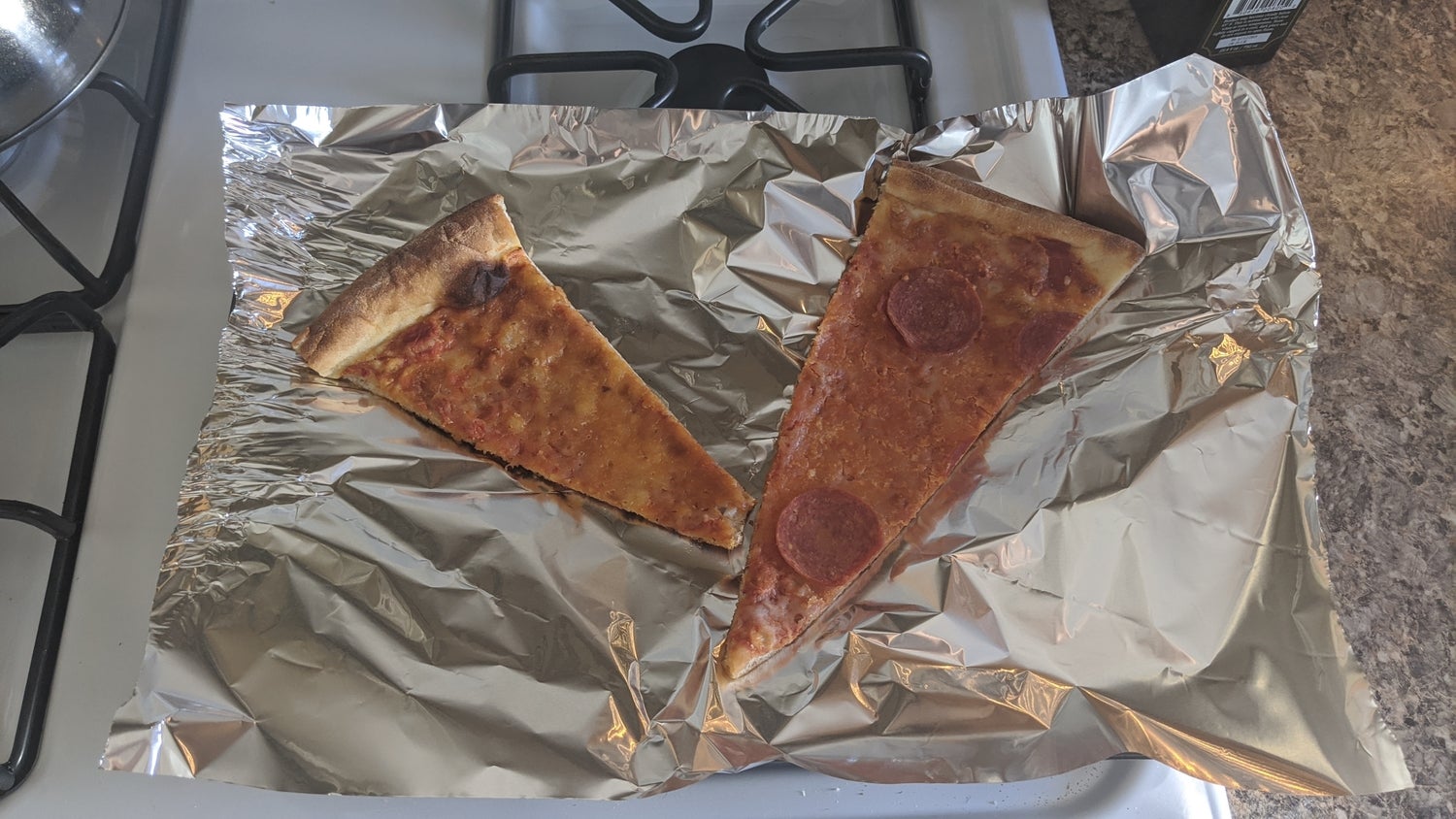 Two slices of pizza (one cheese and one pepperoni) on aluminum foil. When reheating pizza in an oven, never put it straight on the rack.