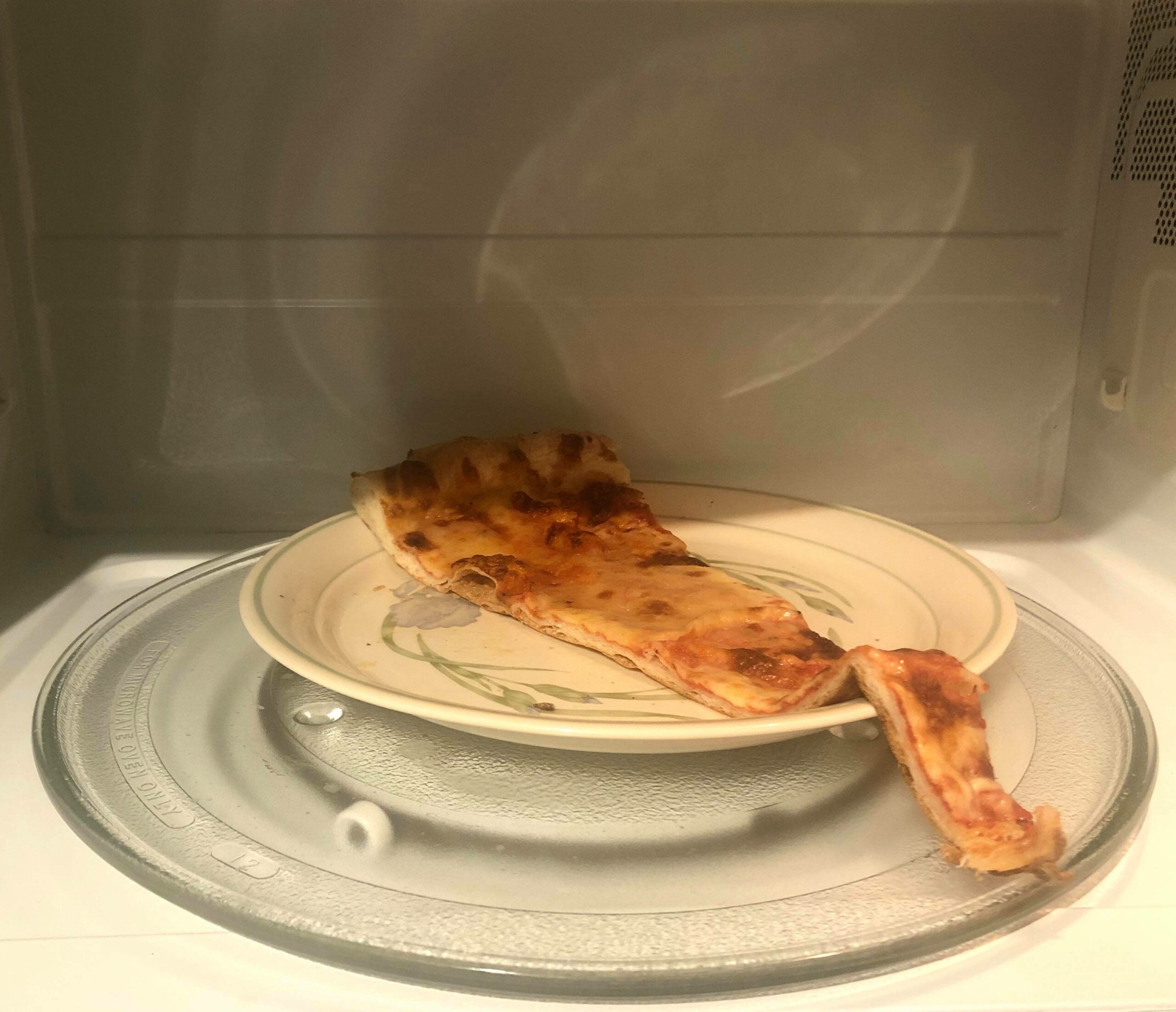 A slice of cheese pizza in the microwave before going to the oven. It's not the best way to heat up pizza, but it's adequate.