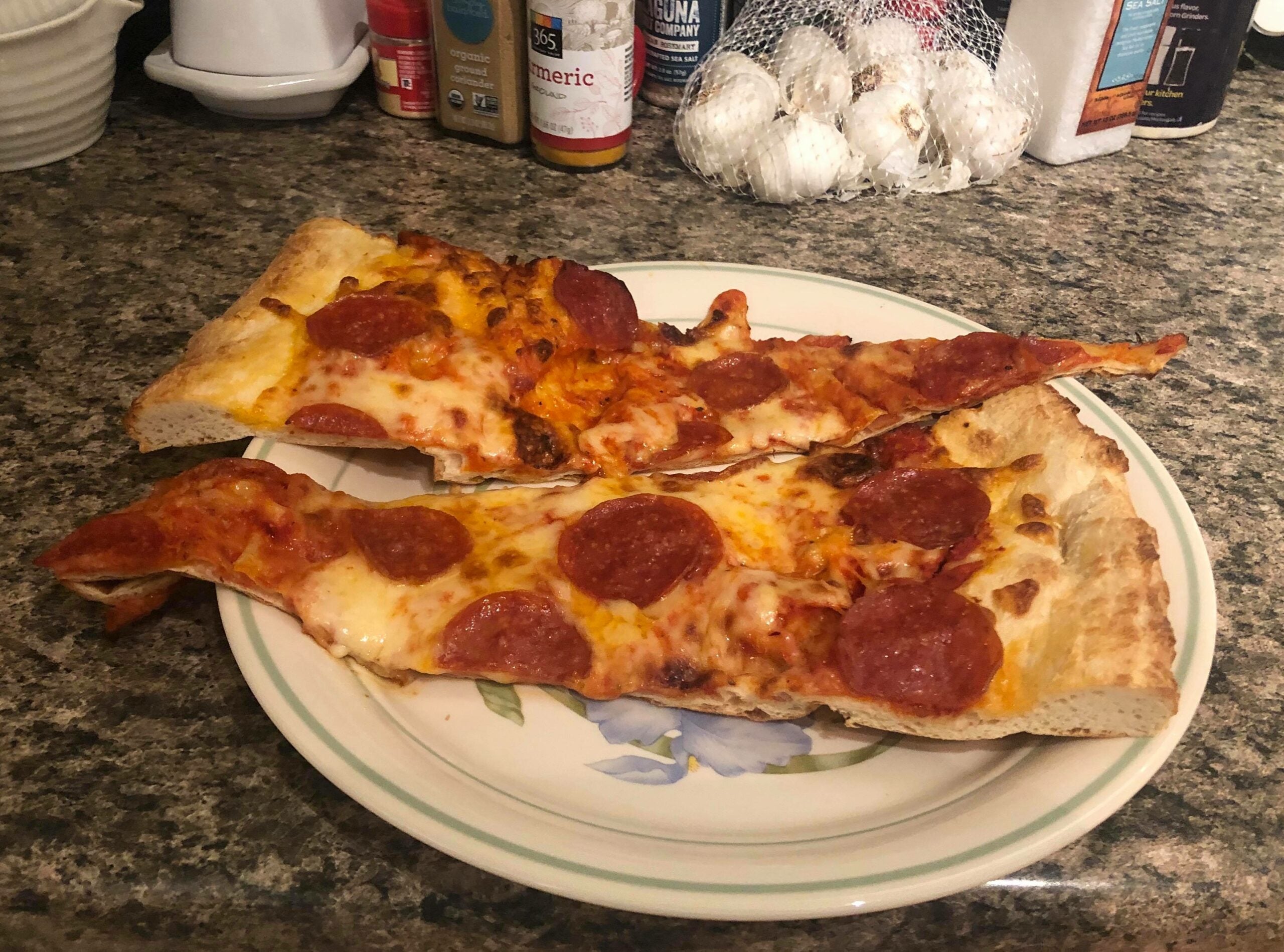 Two slices of pepperoni pizza on a plate after being rebaked as a way to determine the best way to reheat pizza.