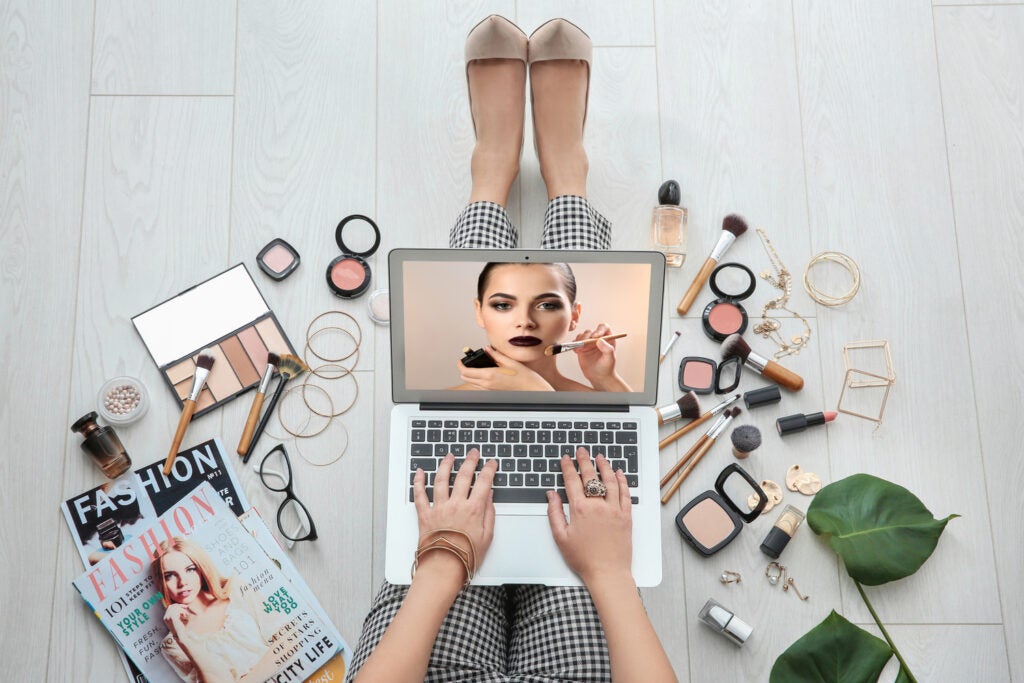 Person sitting on floor with laptop and watching online training for professional makeup artist