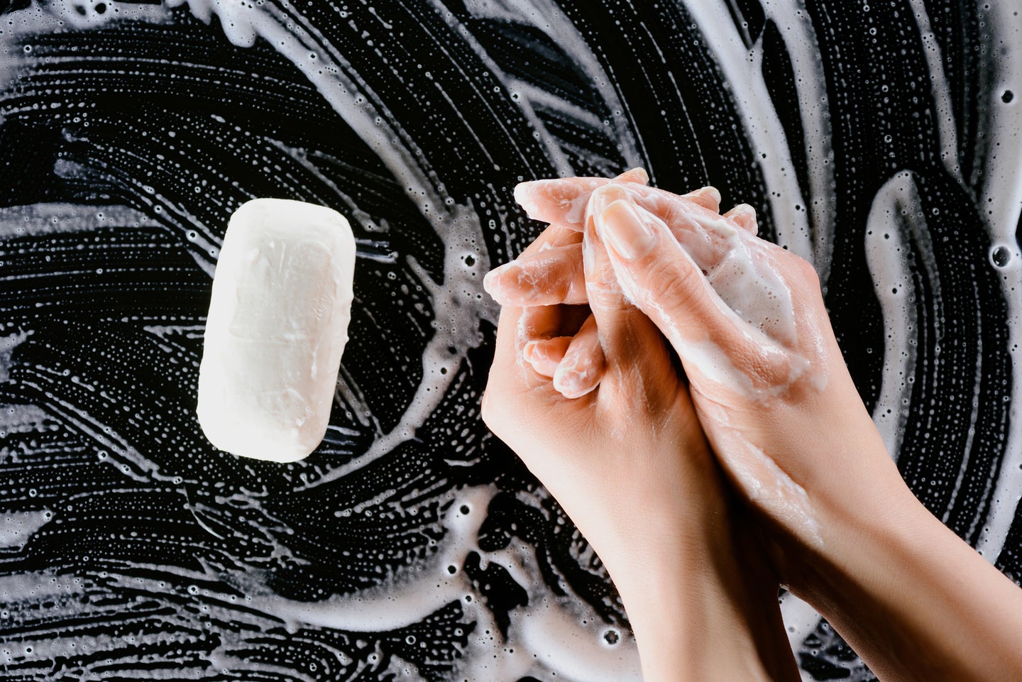 a pair of hands lathering soap on a black background