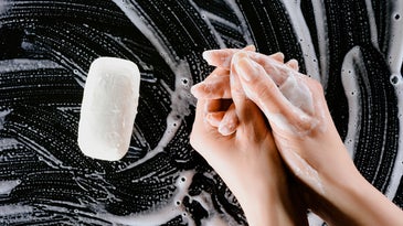 a pair of hands lathering soap on a black background