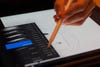 A hand using an iPad with a stylus while drawing and using Adobe Photoshop.