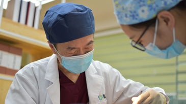 A Chinese doctor standing over a patient