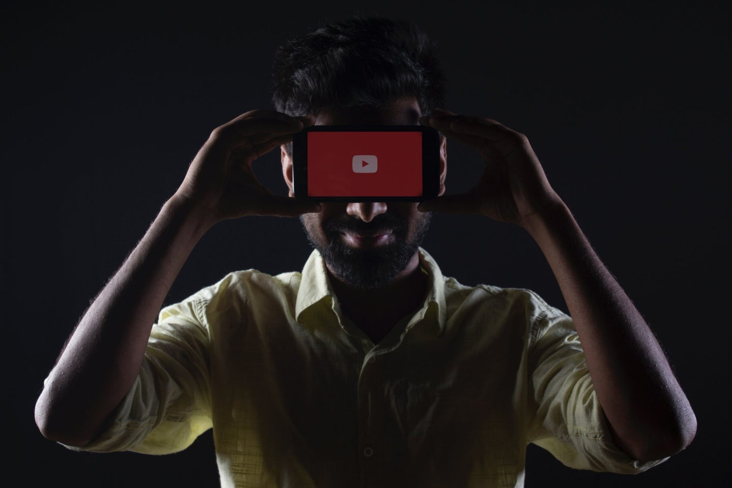 A man holds a smartphone with the YouTube app.
