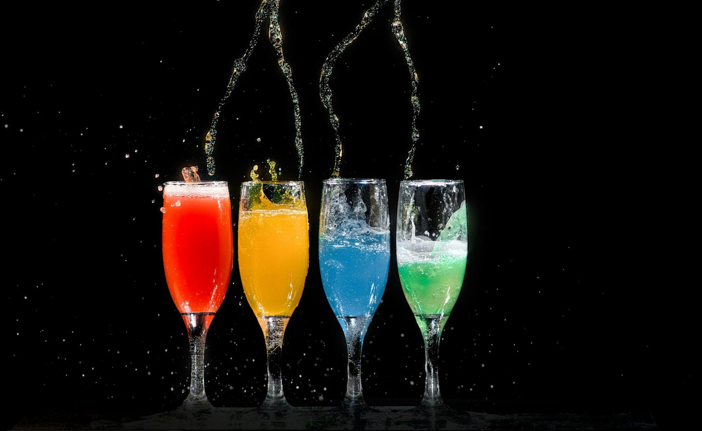 four champagne glasses full of colorful liquid