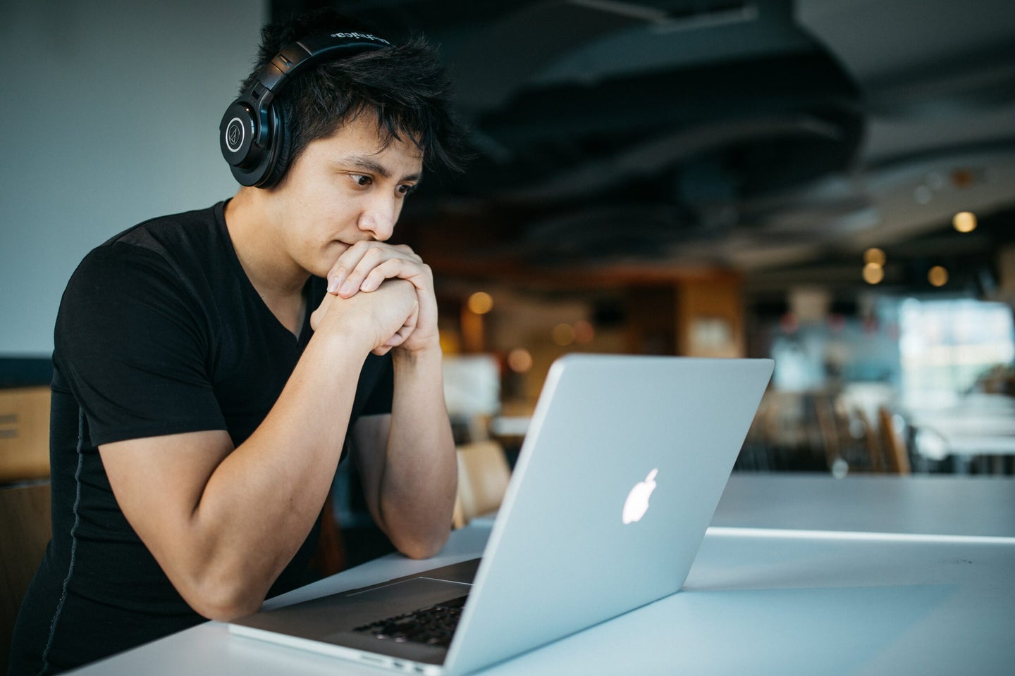 Worker sitting at Mac laptop with wireless headphones on
