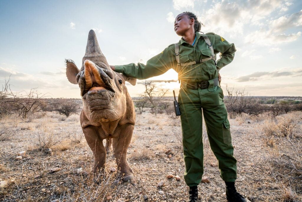 Davis Huber - two-year-old black rhino orphan, poses with ranger Salome at Kenya’s Sera Rhino Sanctuary