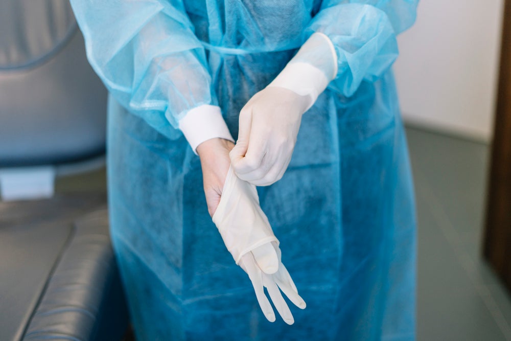 A surgeon takes their disposable gloves off.