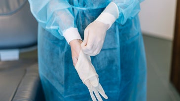 A surgeon takes their disposable gloves off.
