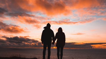 two people holding hands in the sunset