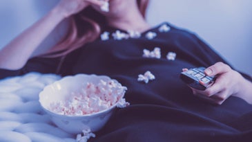 Person watching TV and eating pop corn