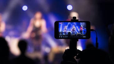 A person holding their phone up at a concert to record or live-stream the performance.