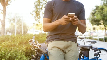 person leaning against his bike with his phone