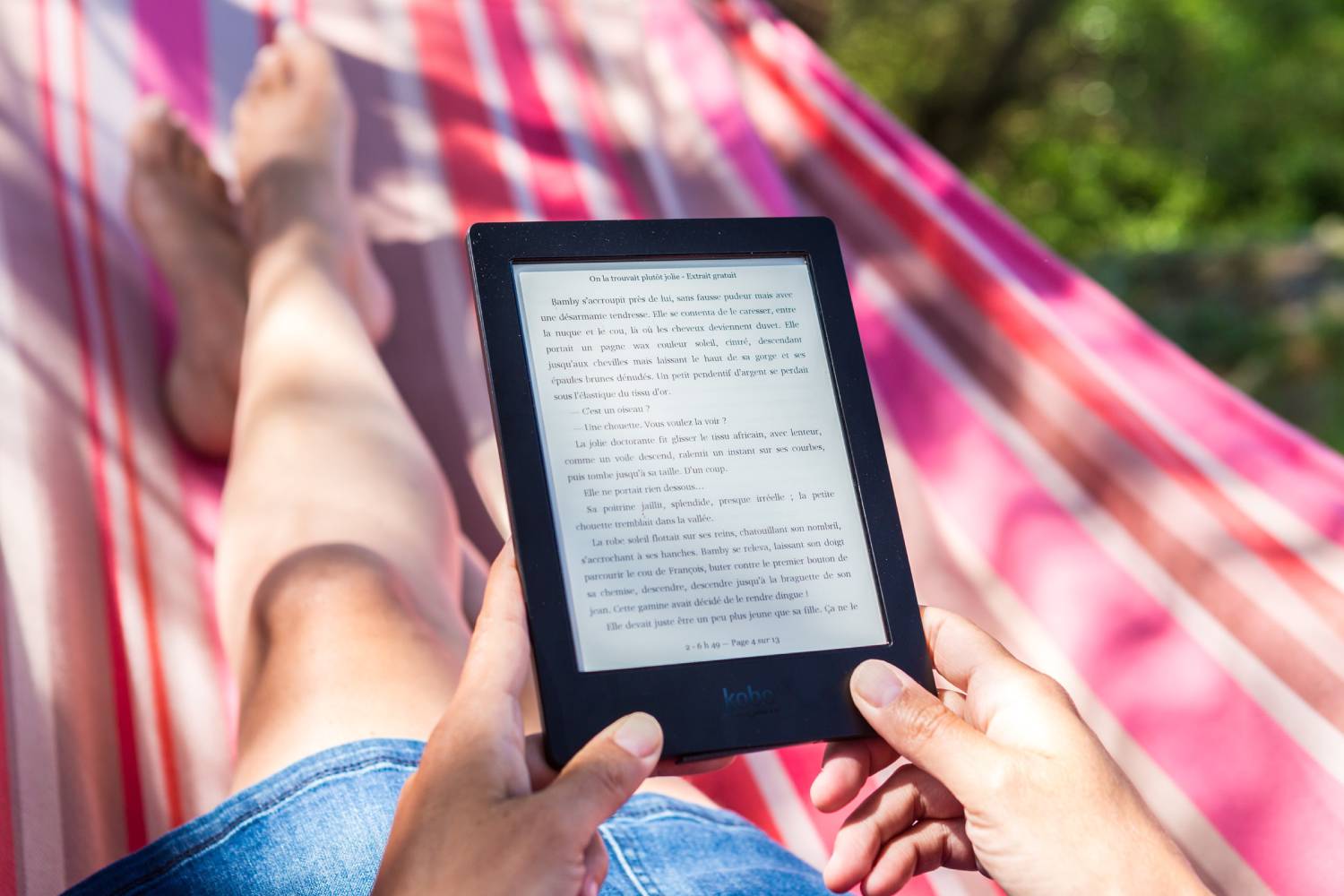 A person reading with an e-reader in a hammock outside.