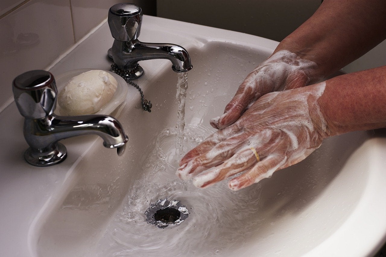 Person lathering hands under a running faucet