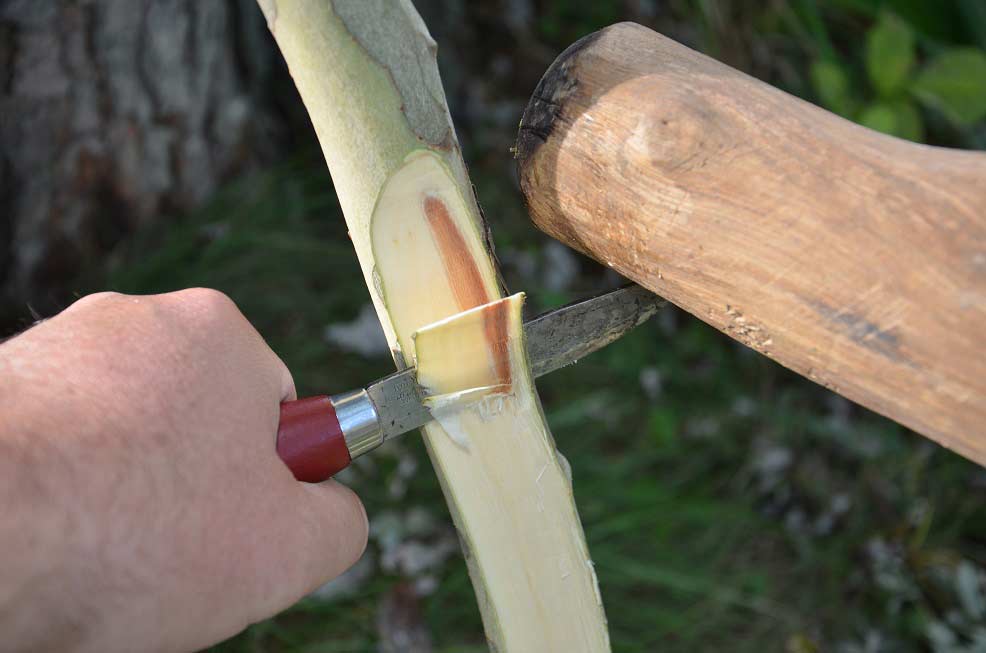 A knife carving out a slice of wood.