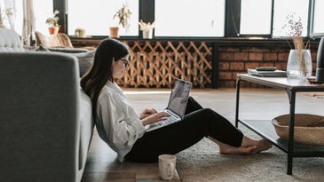A woman working from home on the floor.