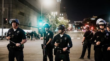 several police officers standing in a road holding weapons