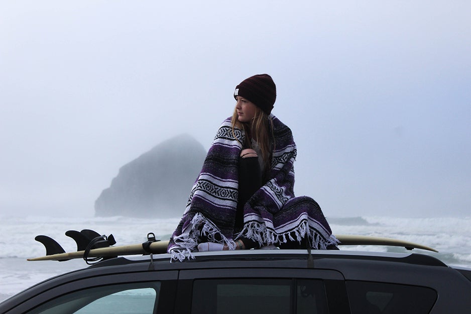 person sitting on top of a car with a blanket
