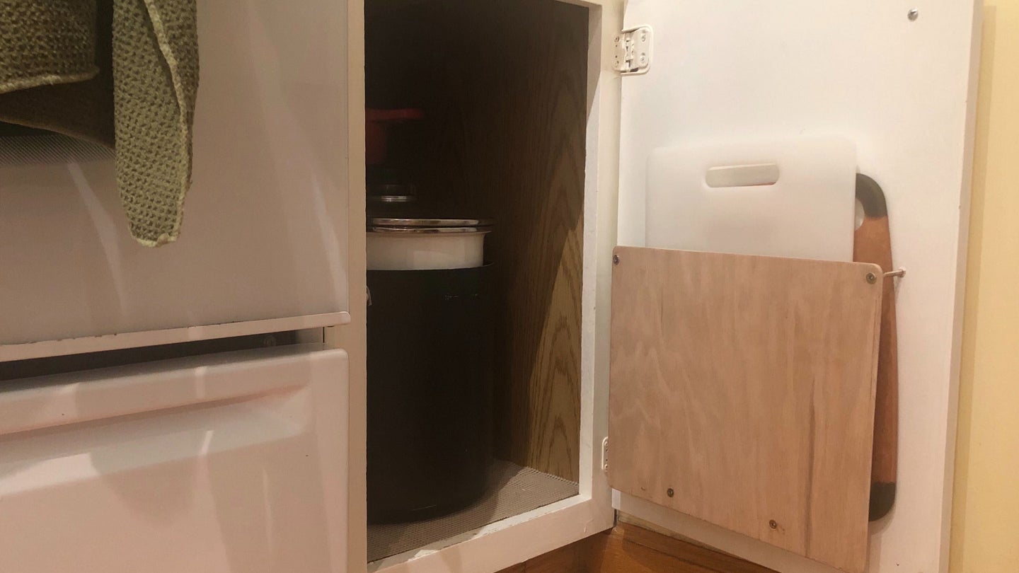 a cutting board storage rack installed on the inside of a kitchen cabinet door