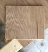 a piece of plywood cut, sanded, and drilled for the face of a DIY cutting board storage rack on the inside of a cabinet door