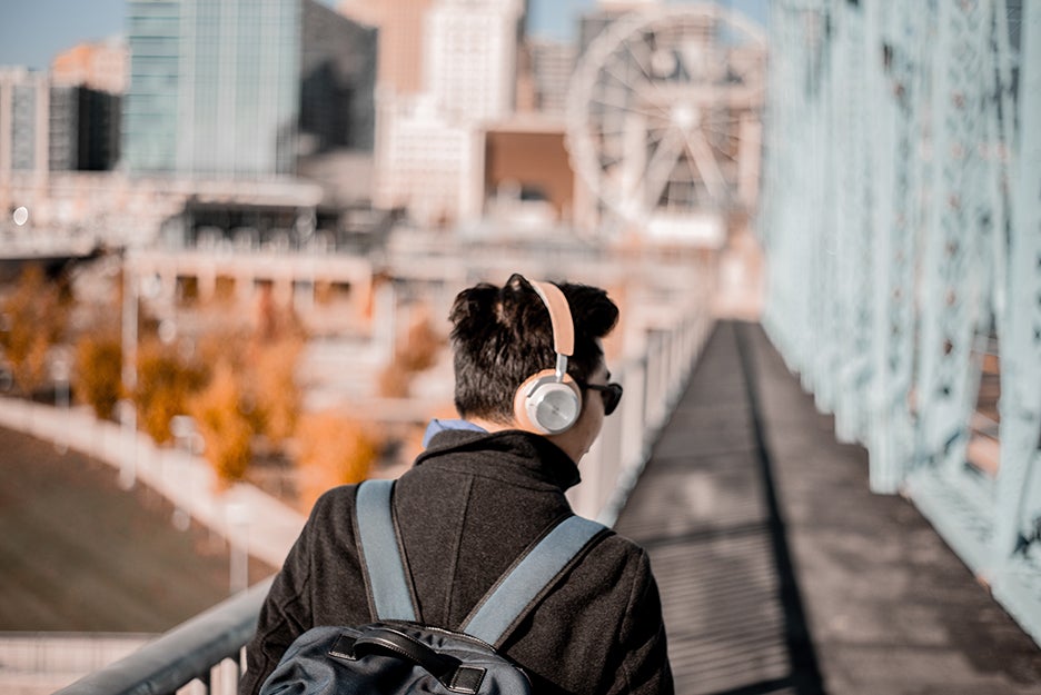 person walking over bridge with headphones