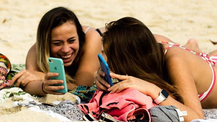 two people on the beach with their phones